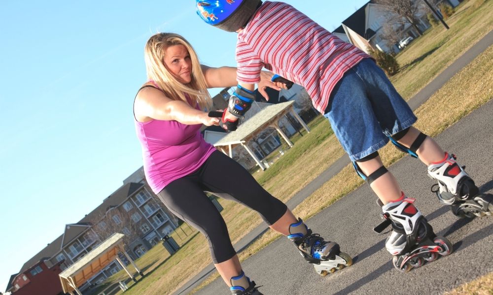 A mom helping a child learn to roller skate.